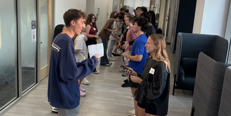 Hallway full of students standing across from each other and talking. 