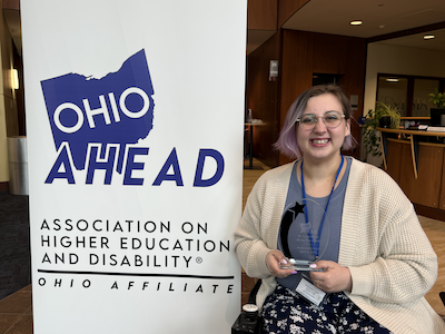Annastashia Blesi holding a crystal award, posing next to an Ohio Ahead banner.