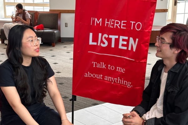 Two students talking, a banner behind them reading "I'm Here to Listen. Talk to me about anything."
