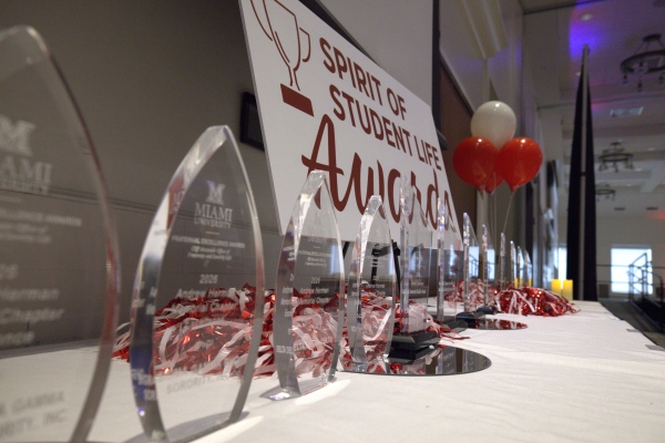 Closeup of a row of crystal awards, the words "Spirit of Student Life" on a banner in the background. 