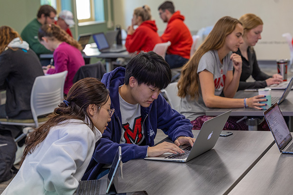 Two students work together on a computer.