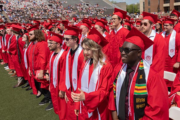 Graduates stand in a row at their commencement cermony.