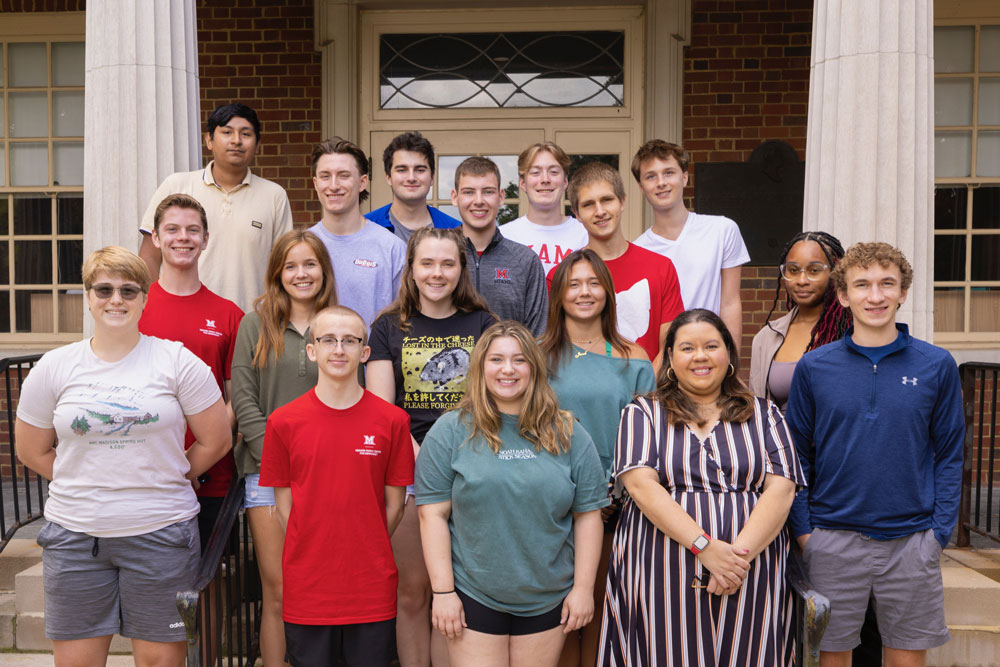 Student participants on pose for group photo on steps of a residence hall