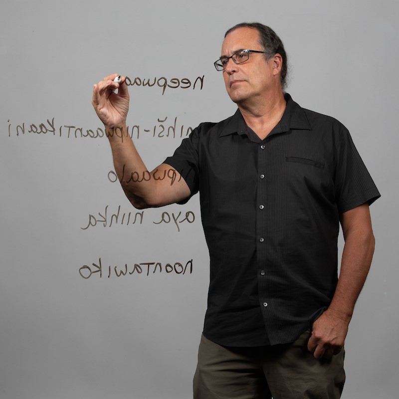 Daryl Baldwin writing some of the myaamia language on a clear board