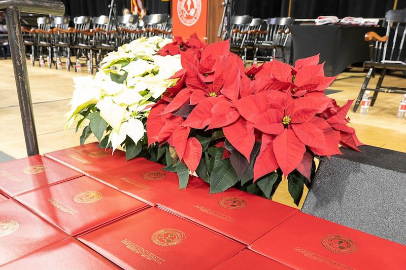 A stack of diplomas ready to to be handed to students on the stage of Millett Hall