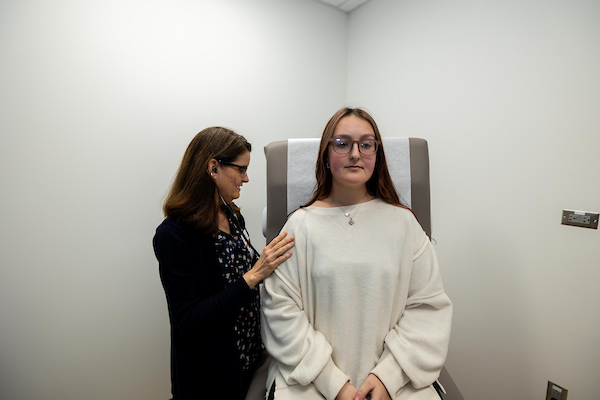 Clinician listens to a student’s breathing during a medical appointment.