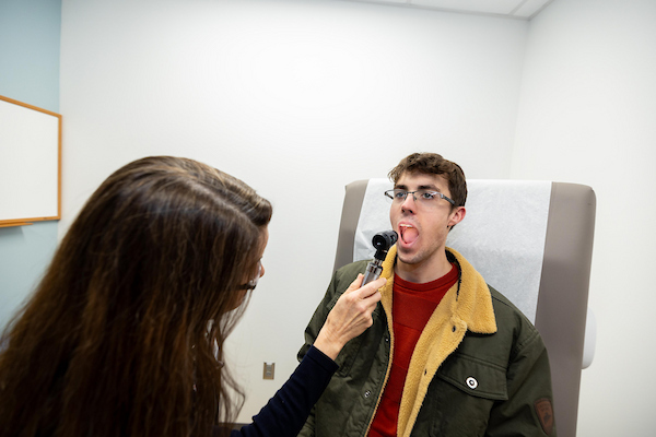 Clinician checks a student’s throat during an exam.