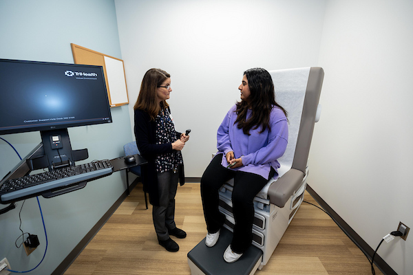 A student is in a patient room talking with a doctor.