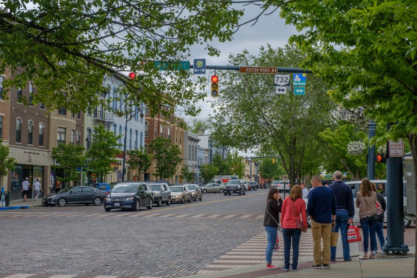 People stand on the sidewalk next to a street in Oxford, Ohio.