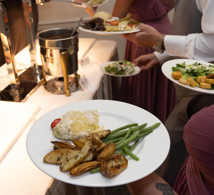 People holding up their plates in line for the roast carving station