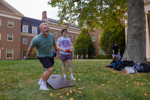 Students playing cornhole in a residential quad