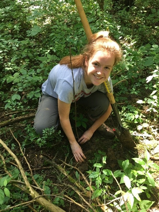 Abby Hay, crouching in a forest.