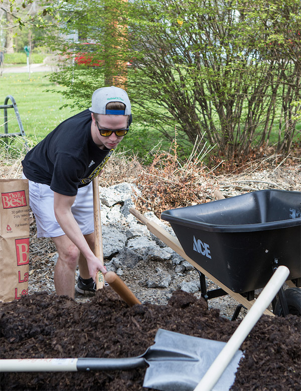 student shoveling mulch outside