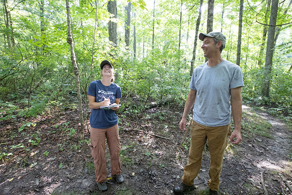Chloe Trimmer and Rob Atkinson look up at trees in the Kramer Woods Loop Trail of the Natural Areas
