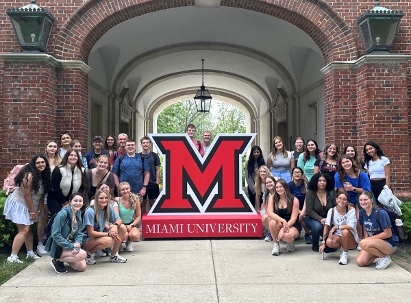 Group of about 30 students posing under the upham arch