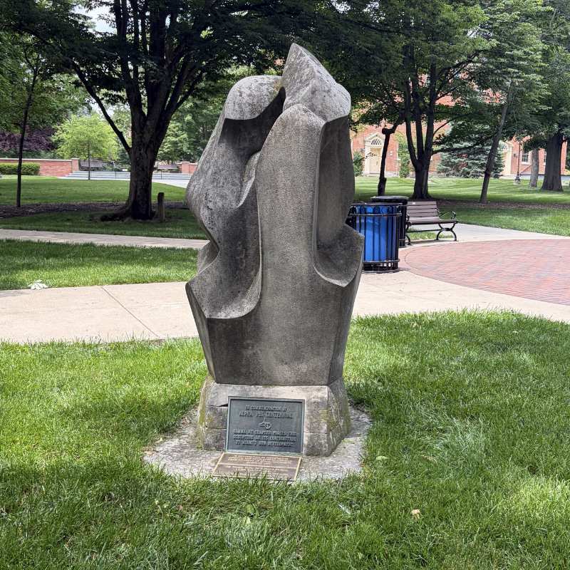 Concrete abstract scupture atop a pedestal on Academic Quad