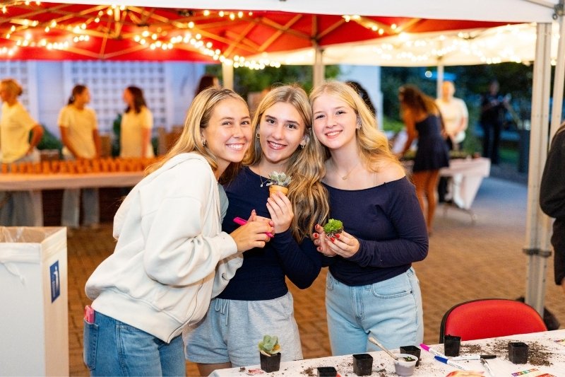 three students holding up succulents from an on-campus event.