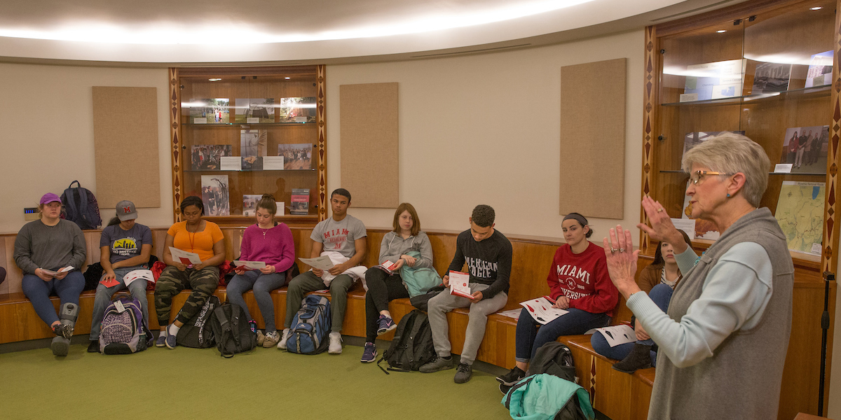 Bobbe Burke giving a lecture to students sitting on the benches around the circular room