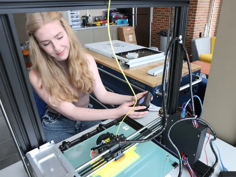 Student working in lab with 3D printer.