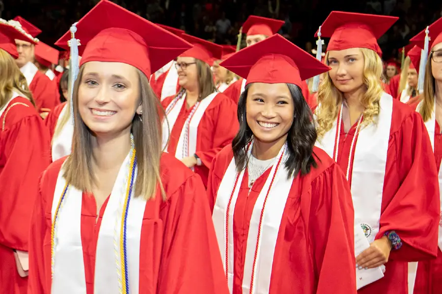 Students in red caps and gowns at graduation.