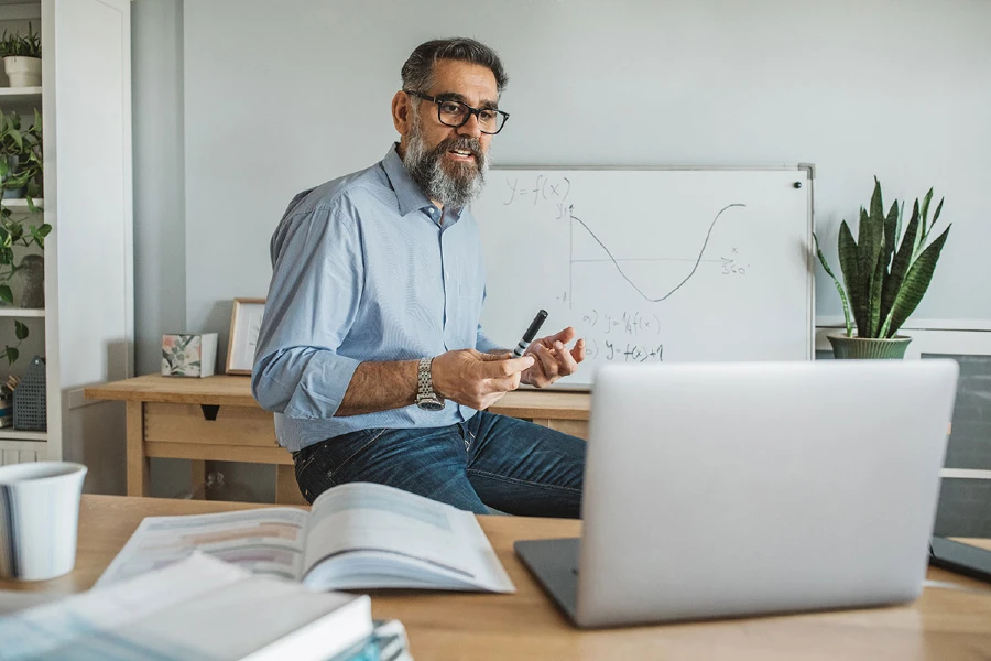 A faculty member presenting to laptop sitting on his desk.