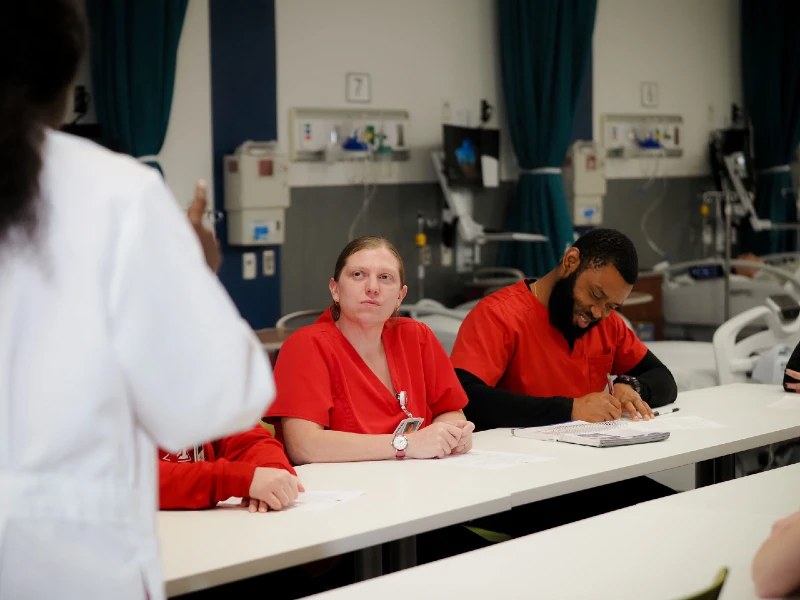 Nursing students working in classroom with instructor up front.