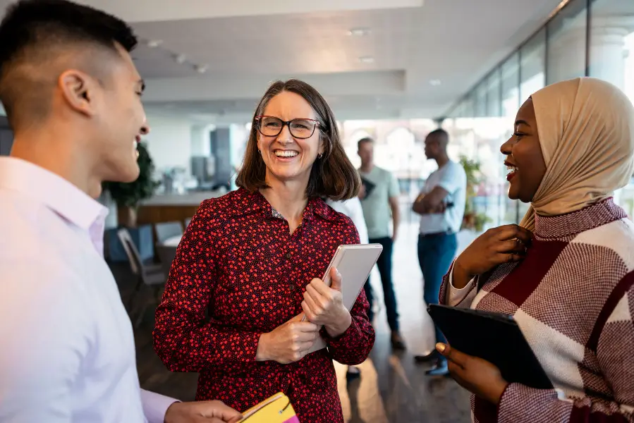 Three adults standing in lobby talking.