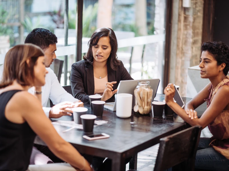 A group sitting at table working on laptops having a discussion.