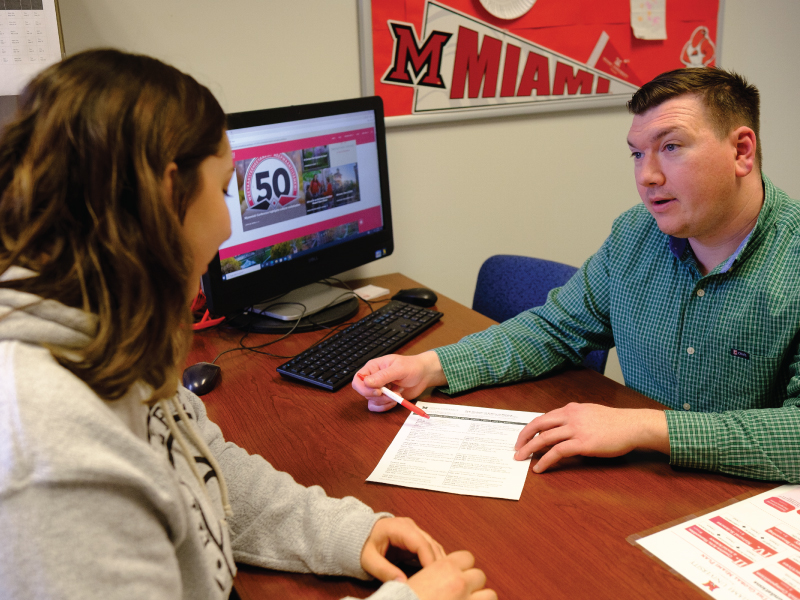 Academic advisor meeting with a student in his office.