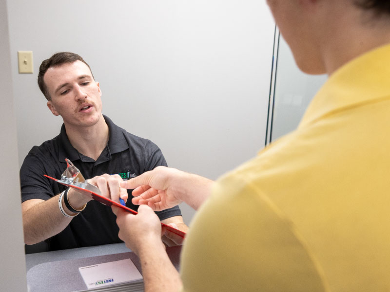 Student handing someone paper work after checking in at a front desk