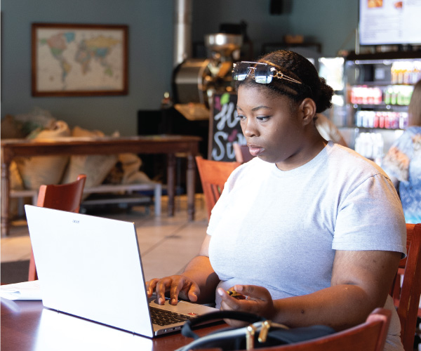 A student working on her laptop in a coffee shop. 