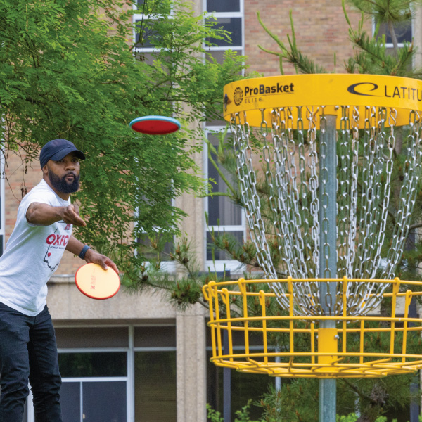 A player throwing a disc towards the disc golf basket.