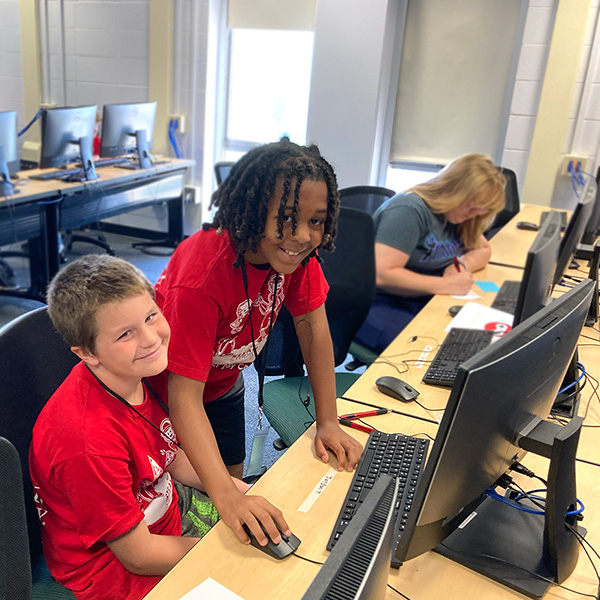 Two campers using code to build a computer game