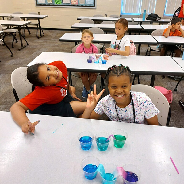 Two girls observing an experiment with colored dyes