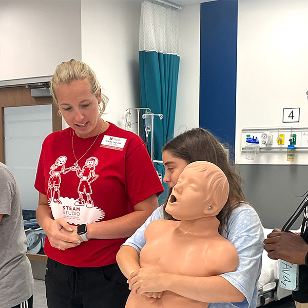 A camper learning the Heimlich Maneuver with her counselor
