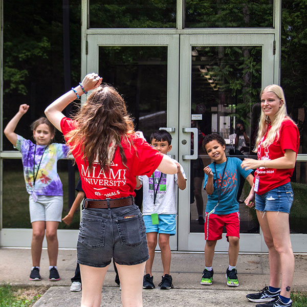 STEAM counselor leading a group of campers in a dancing  activity