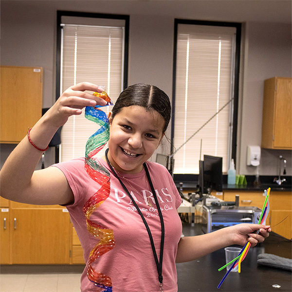A teen camper showing off her colorful twist sculpture