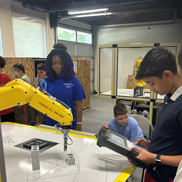 Campers learning how to operate a robotic arm