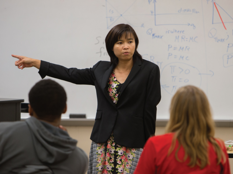 A professor standing in the front of the room teaching the students.