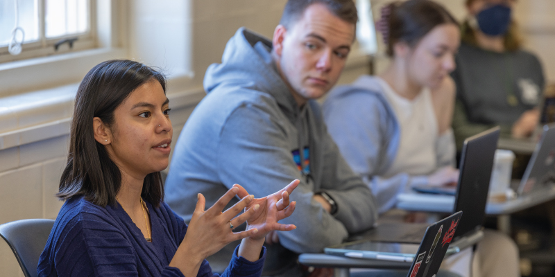 A student sitting in class contributing to a discussion led by the faculty.