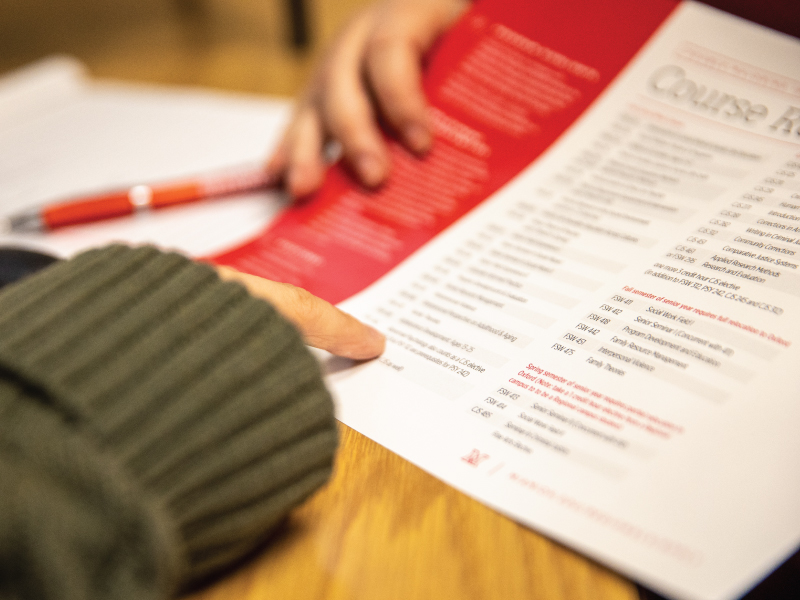 A student pointing at the course requirements for a major. 