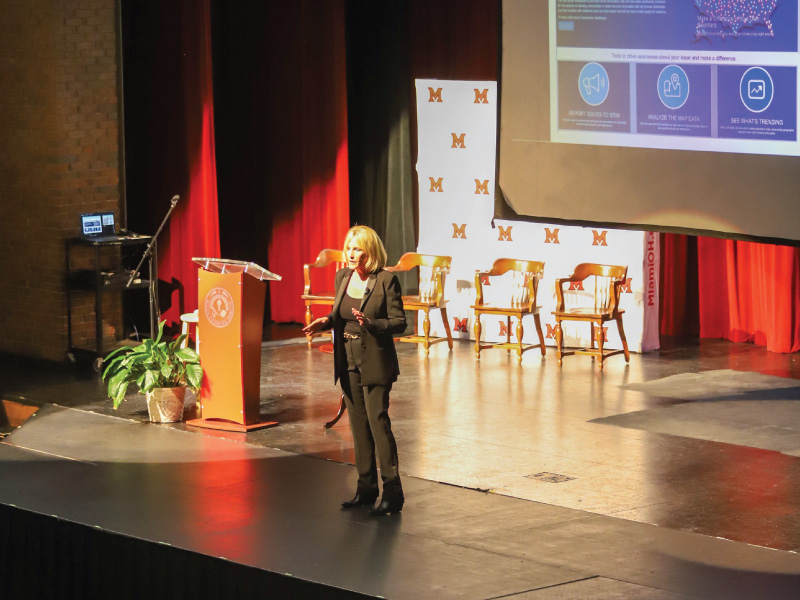 Erin Brockovich speaking on stage at the Middletown Campus Dave Finkelman Auditorium