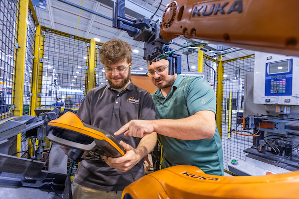 Xavier Brown working with his supervisor on a machine at Shape Corp.