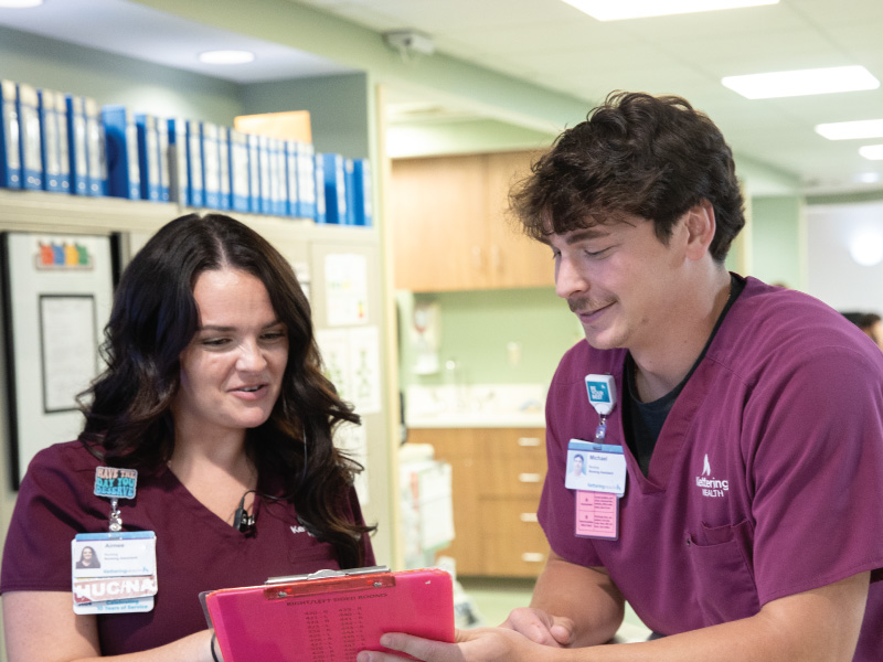 Michael Hundley Work+ Nursing student and his superviosor at Kettering Health looking at a clipboard together. 