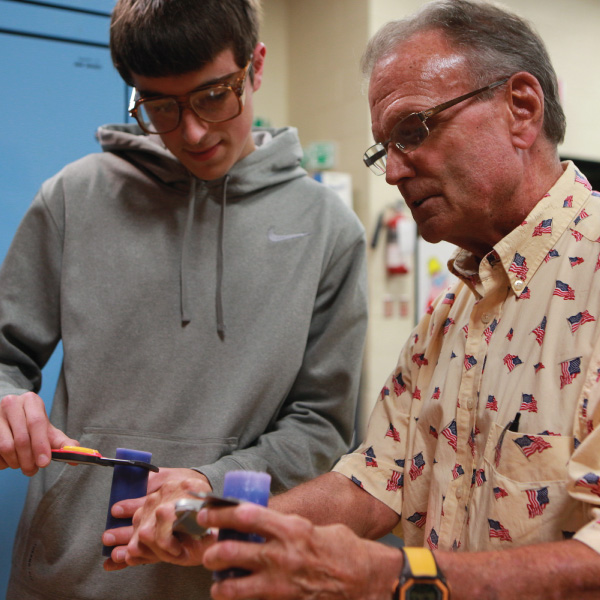 Rob Speckert, Emeritus Professor with student in ENT lab showing him how to use a tool.