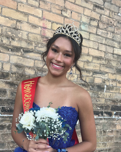 Kaydence Young in a dress and crown holding flowers for homecoming.