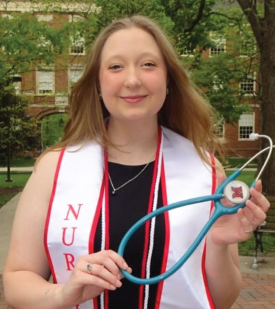 Bailey Ingle in her cap and gown holding her stethoscope