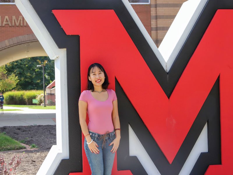 Mona Shao standing in front of the large M on the Hamilton campus.