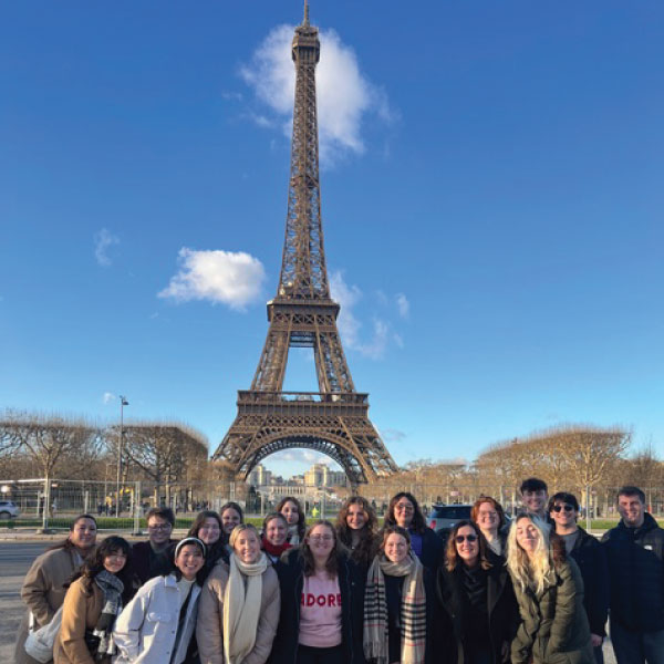 Group of students standing in front of the Eiffel Tower in Paris.