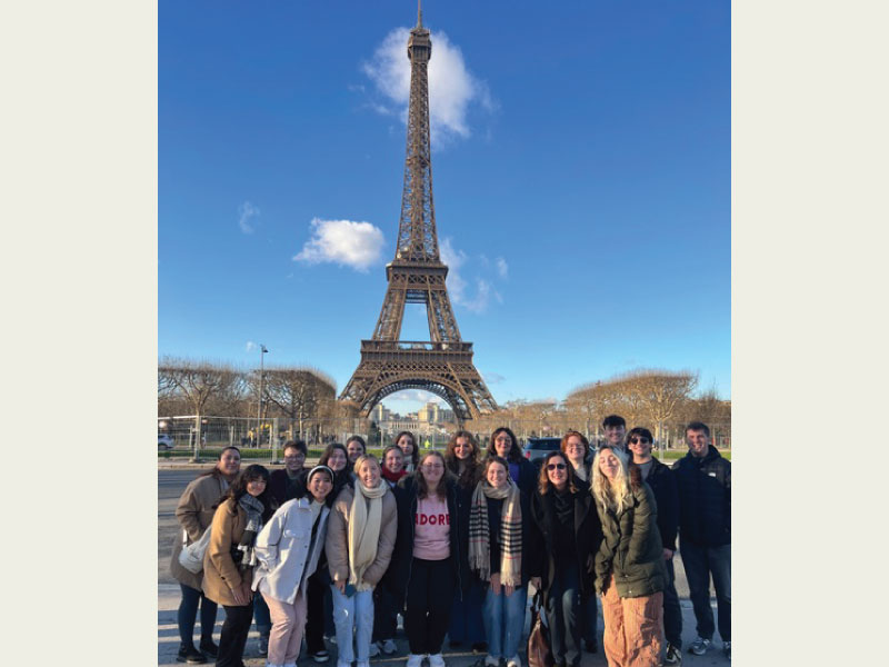 Group of students standing in front of the Eiffel Tower in Paris.